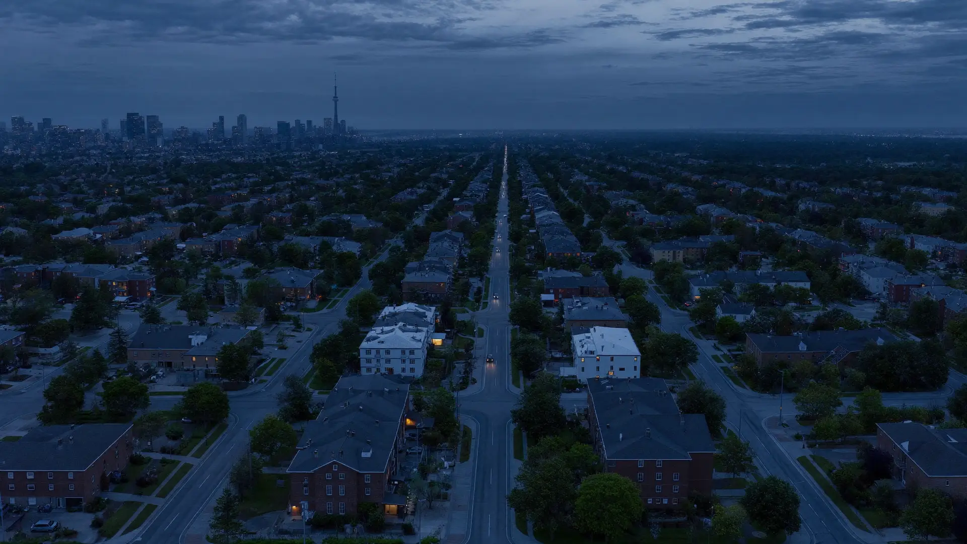 Toronto at dusk from above - a residential street running toward the downtown skyline and the CN Tower